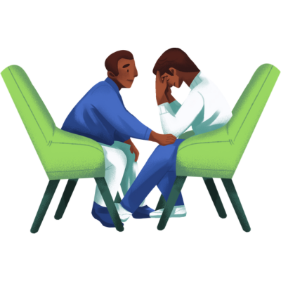 Two people sit facing each other in green chairs. The person on the left is touching the other on the knee as a supportive gesture. The person on the right is distressed and upset, holding their face in their hands and looking downward.